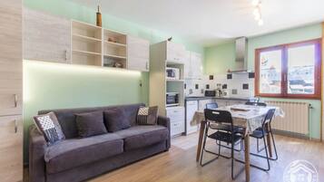 Un espace de vie compact comprenant un canapé, une table à manger et une kitchenette.