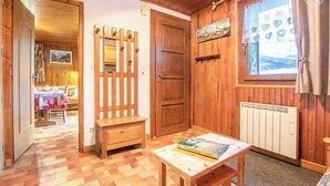 Habitació acollidora amb parets i porta de fusta, una taula amb un llibre, un radiador i una finestra amb cortines.