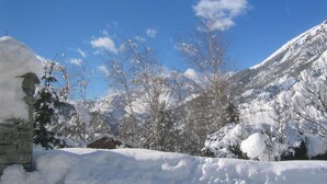 Paisatge nevós amb un edifici de pedra i arbres.