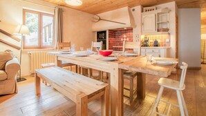 Un comedor acogedor con mobiliario de madera, un cuenco rojo y una cocina al fondo.