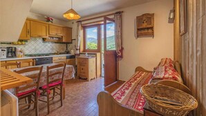A cozy kitchen with wooden cabinets, a dining table, and a large window. - LA BERTINA - MERIBEL LES ALLUES (MERIBEL LES ALLUES)