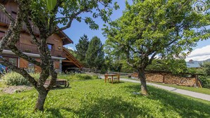 A wooden building with a balcony, surrounded by lush greenery and a stone wall. - LA BERTINA - MERIBEL LES ALLUES (MERIBEL LES ALLUES)