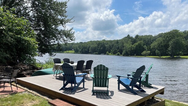A deck with outdoor furniture overlooking a lake, surrounded by trees. - Stunning Lakefront Escape! Book Your Dream Getaway! (Woodstock)