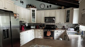 A kitchen with white cabinets, stainless steel appliances, a microwave, and a clock on the wall. - Stunning Lakefront Escape! Book Your Dream Getaway! (Woodstock)