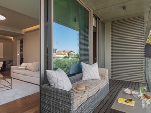 Ein modernes Wohnzimmer mit einer Couch, einem Esstisch mit einem Getränk und Blick ins Freie.