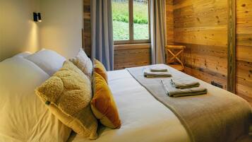Une pièce de cabane en bois comprenant un lit, des oreillers et une fenêtre avec des rideaux.