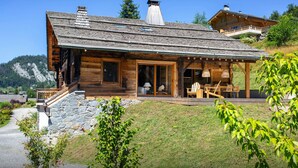 Eine Holzhütte mit steinernen Fundamenten, einer Veranda und einem Berggrund.