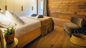 Ein Schlafzimmer mit einem Bett, einem Sessel, einem kleinen Tisch mit einer Pflanze und einem gewobenen Korb.