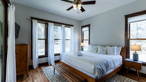 Un dormitorio con una cama de madera, un ventilador de techo y una mesita de noche con lámpara.