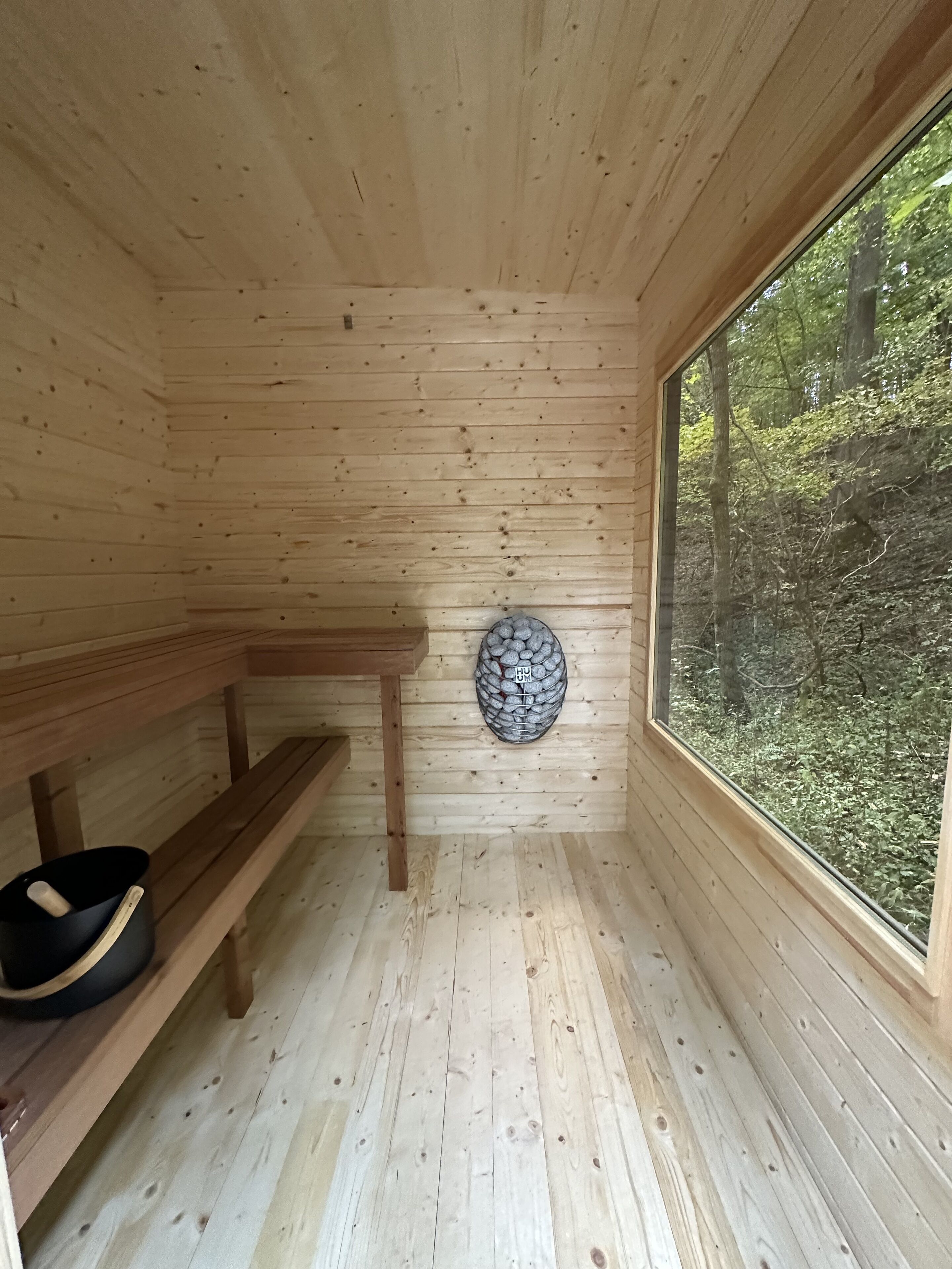 Une cabane en bois avec un banc, une petite table et une fenêtre donnant sur la forêt.