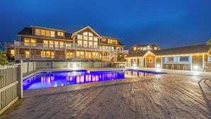 A large, multi-story house with a swimming pool and wooden deck. - Hemingway & Mark Twain Estate | Weddings & Events | 32BR Sleeps 72 | OBX (Corolla)