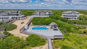 A large beachfront property with multiple houses, a swimming pool, and a wooden deck.