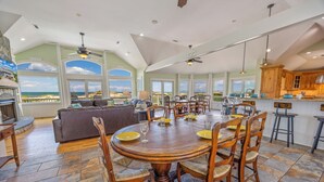 A spacious dining area with a large wooden table and chairs, a cozy seating area with a sofa, and a kitchen with wooden cabinets.