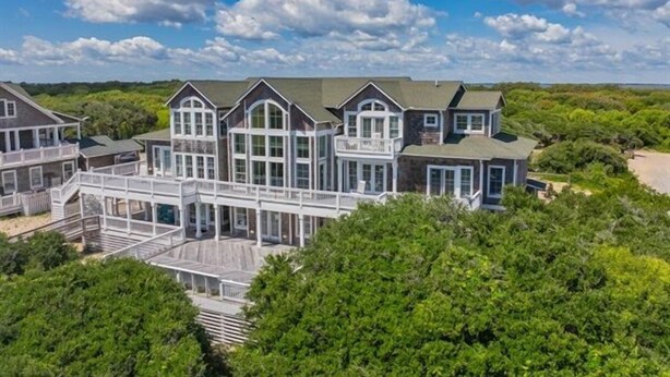 A large, multi-story house with a covered deck and multiple windows.