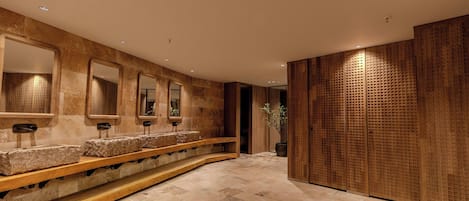 A modern bathroom with stone sinks, mirrors, and a wooden panel wall.