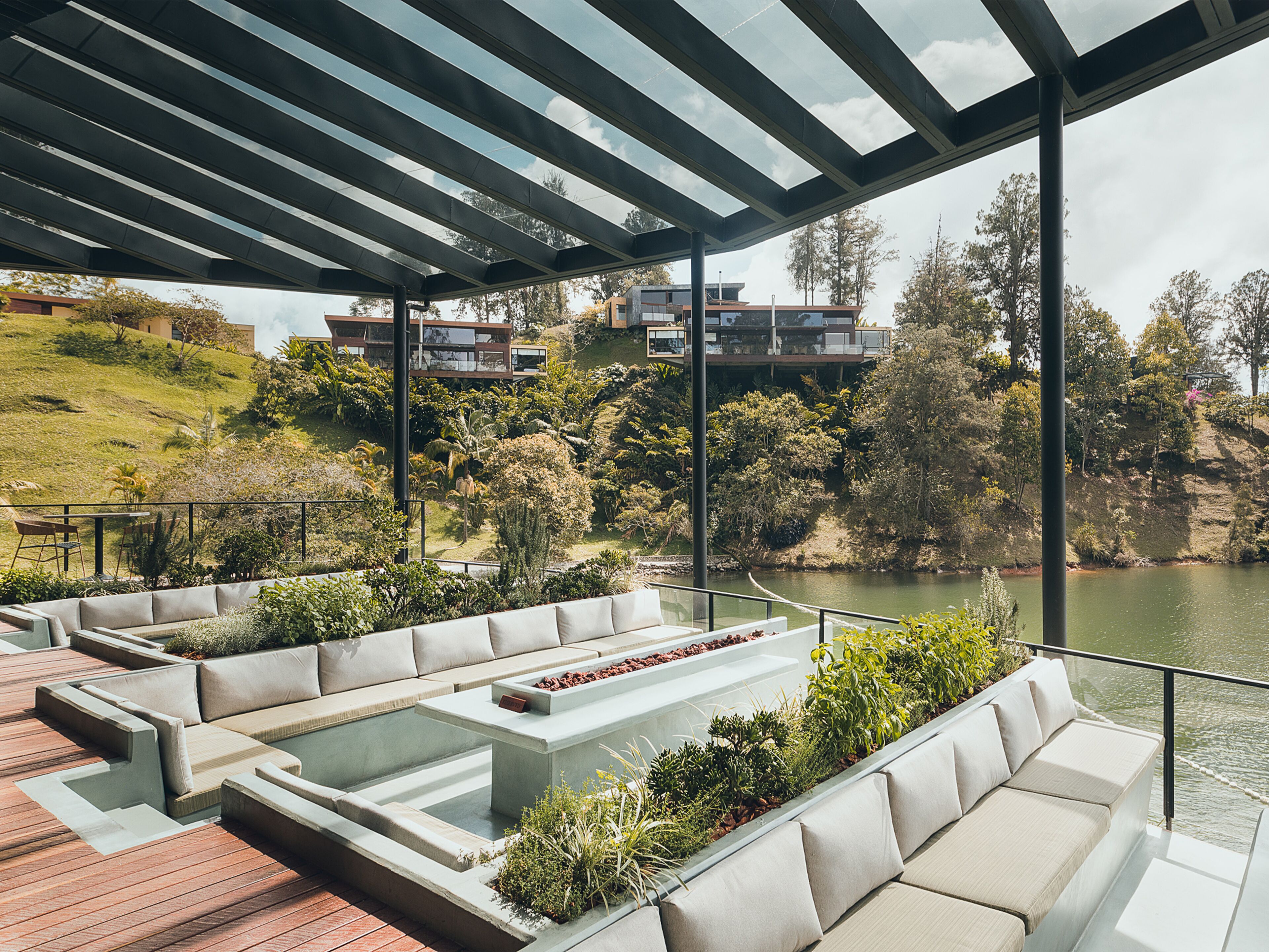 A modern outdoor seating area with a view of a river and hills.