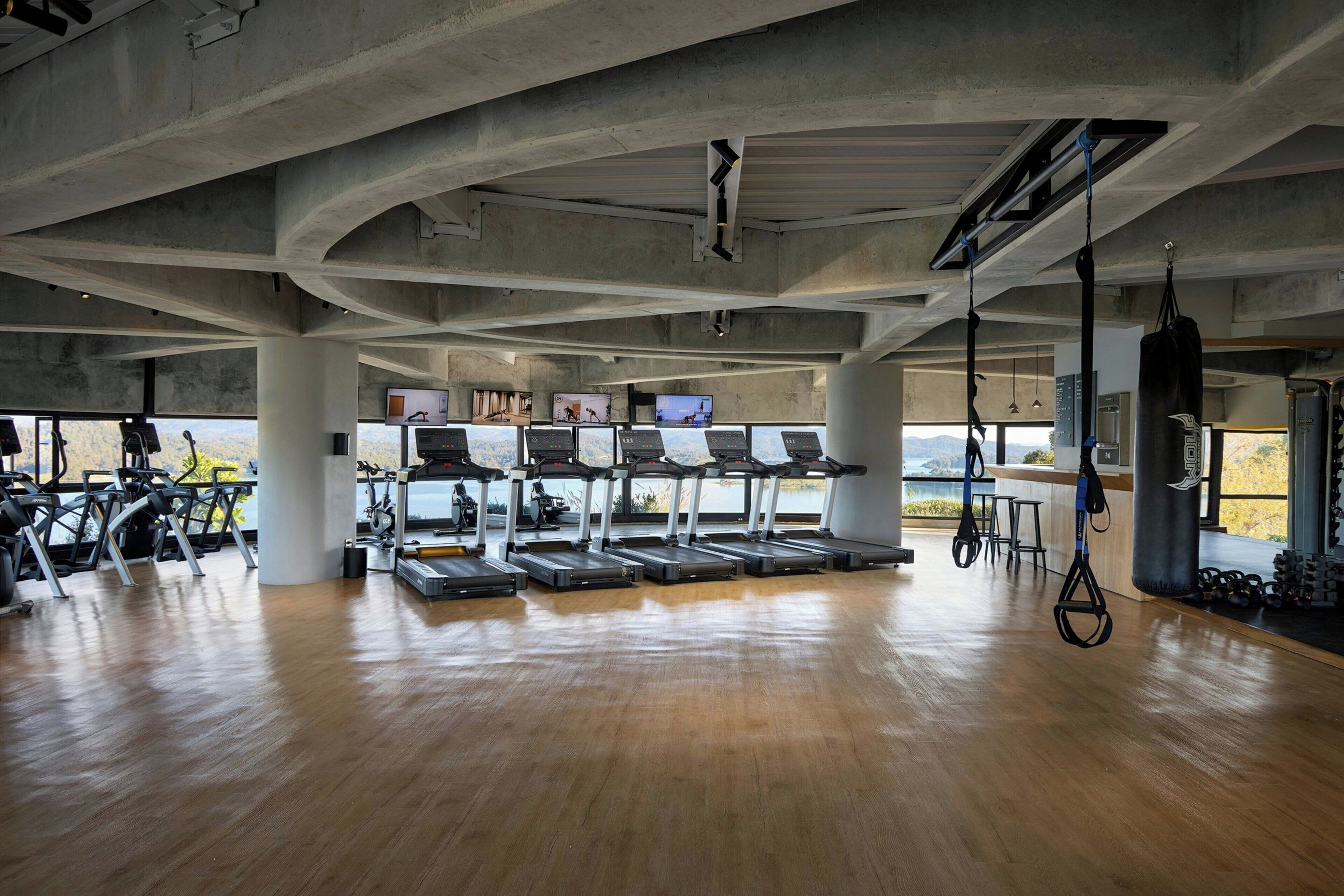 A gym with treadmills, stationary bikes, and a punching bag.