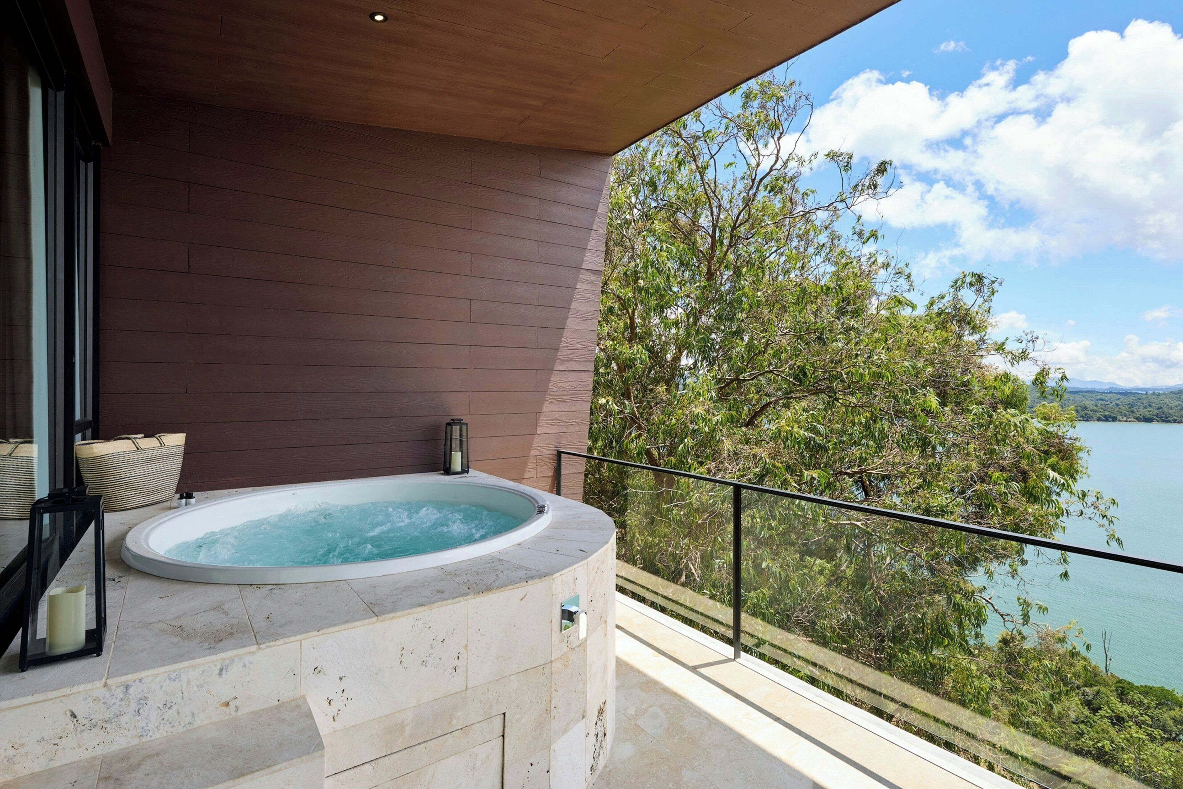 A hot tub on a balcony with a view of a lake and trees.