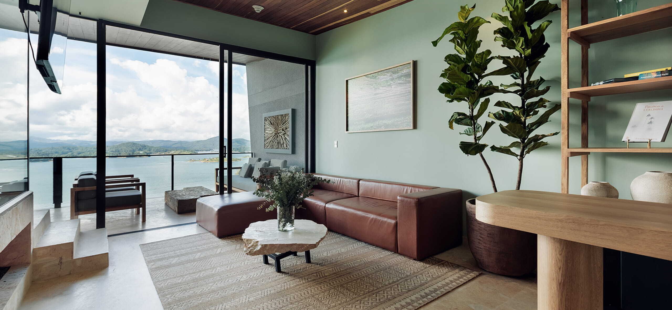 Una sala de estar moderna con un sofá de cuero, una mesa de centro y una estantería. Hay un ventanal que ofrece vistas al exterior.