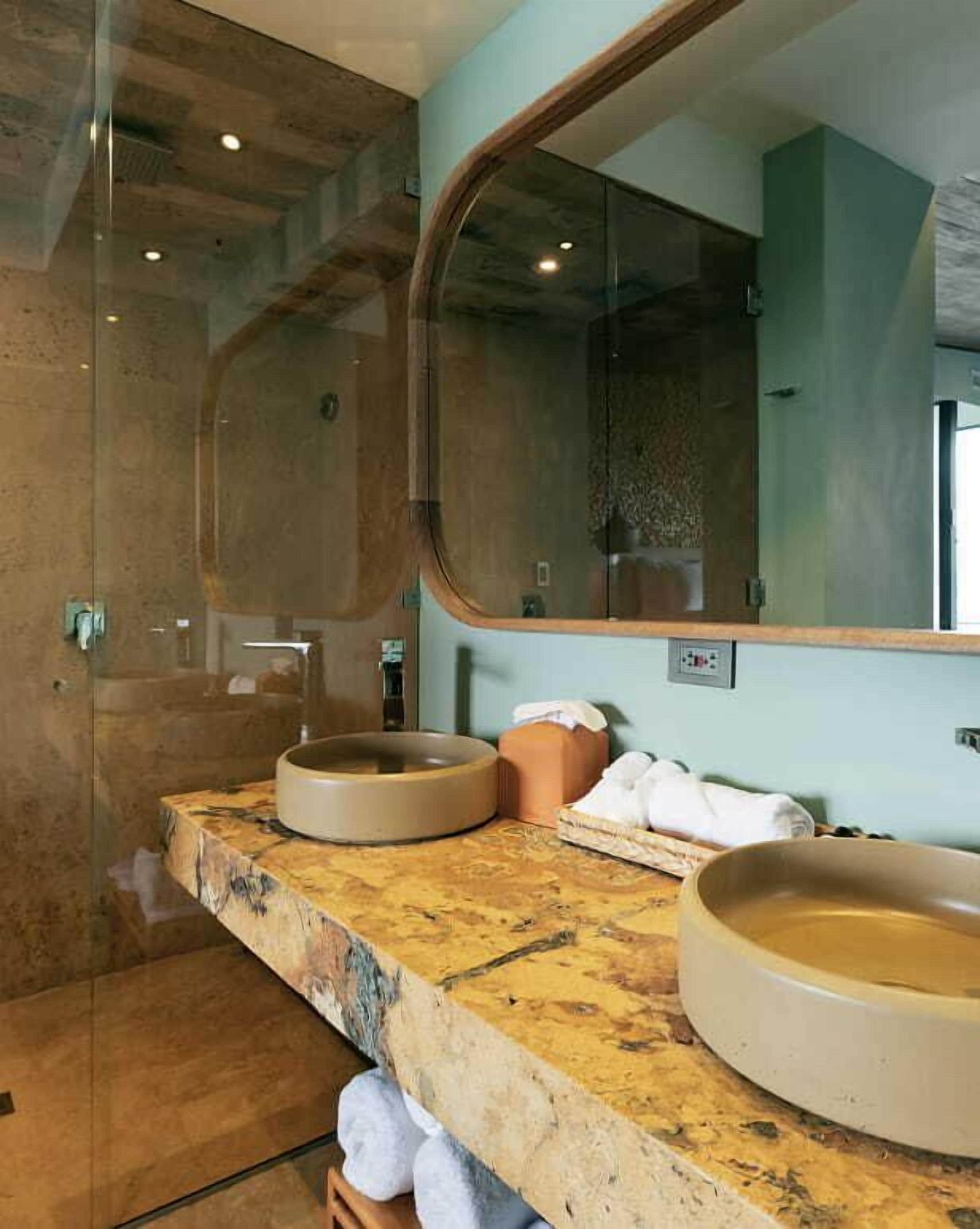 Ein Badezimmer mit zwei Waschbecken, einem großen Spiegel und einer Duschkabine.