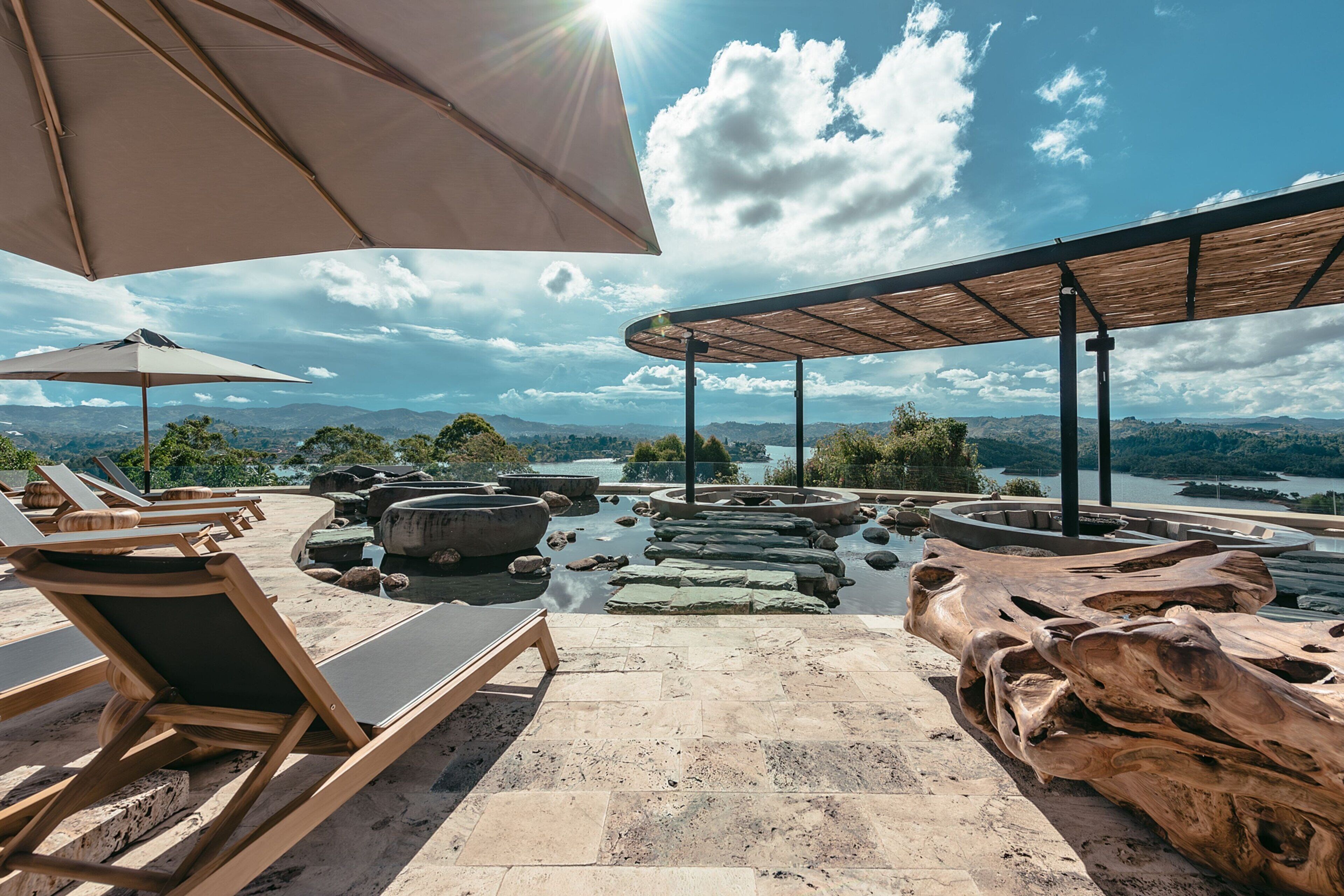 Una terrazza con poltrone relax e vista su un lago e montagne.
