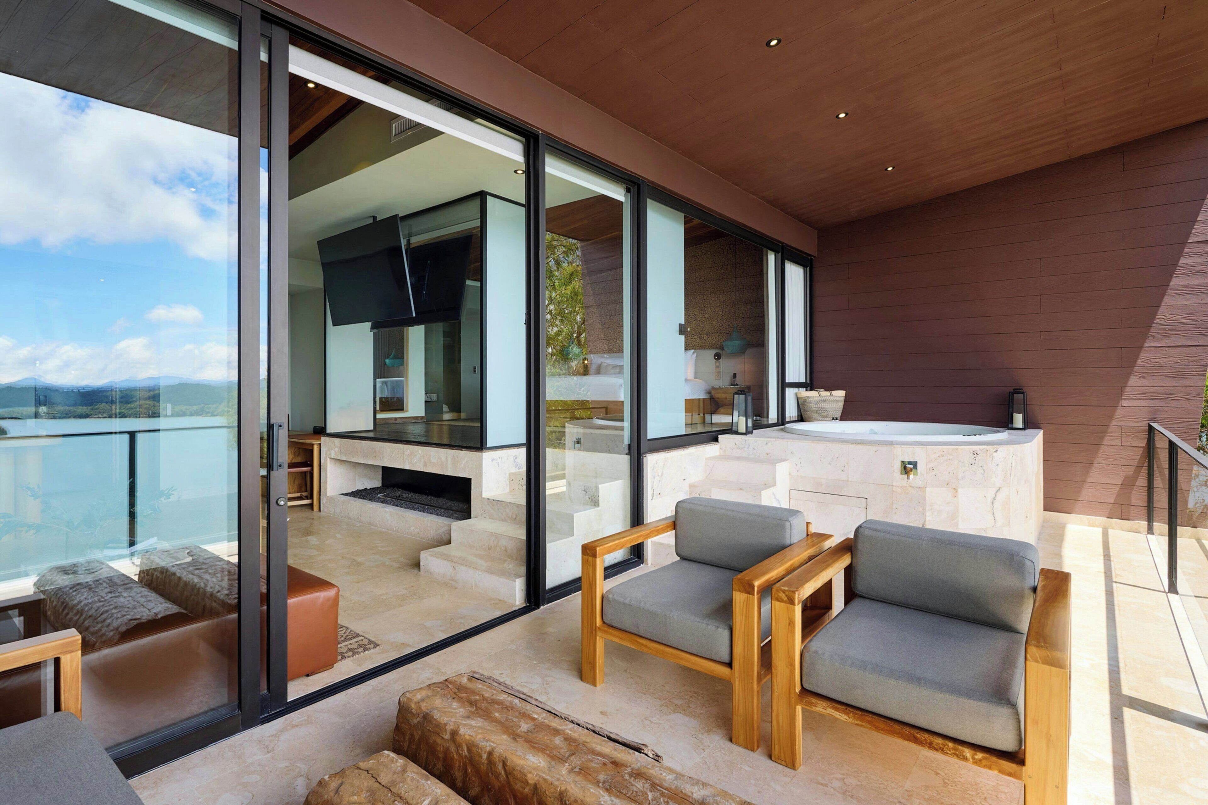 Un espacio exterior moderno con puertas de vidrio que dan a una cocina y un jacuzzi.