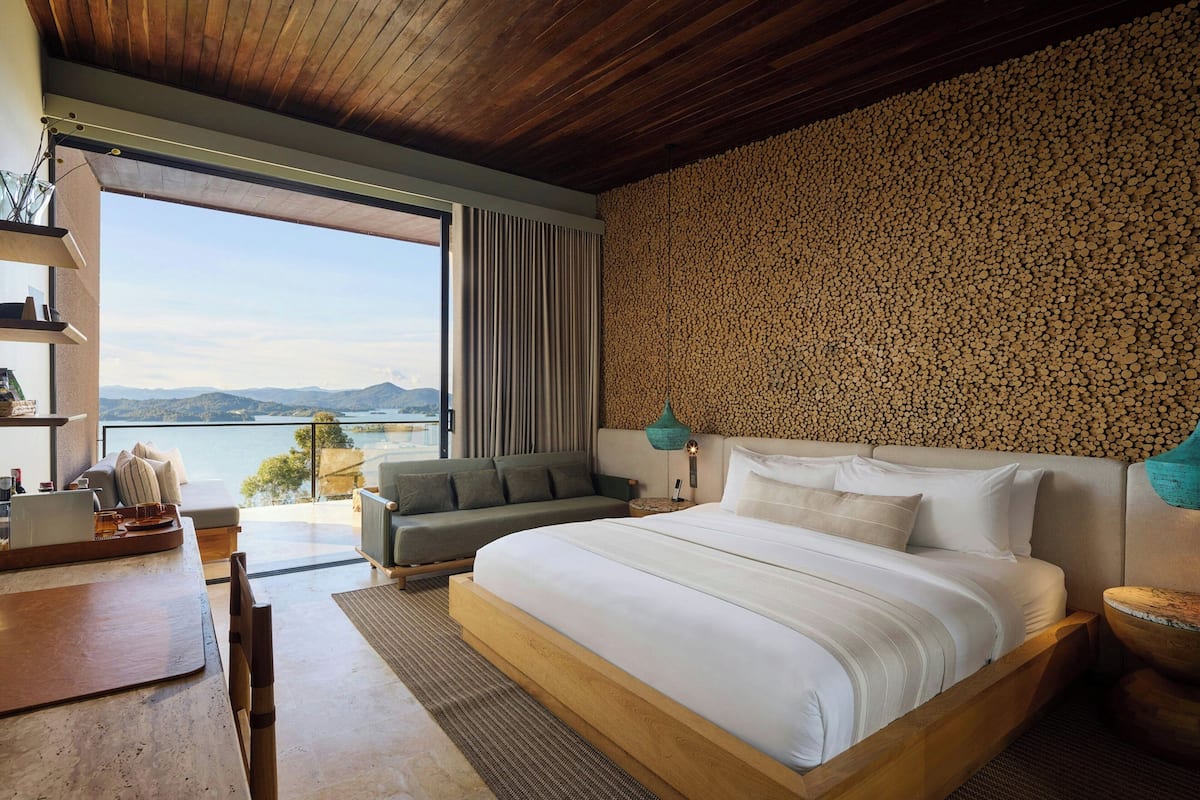 Un dormitorio moderno con una cama grande, un sofá, un escritorio y vistas al exterior.