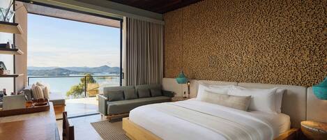 Un dormitorio moderno con una cama grande, un sofá, un escritorio y vistas al exterior.