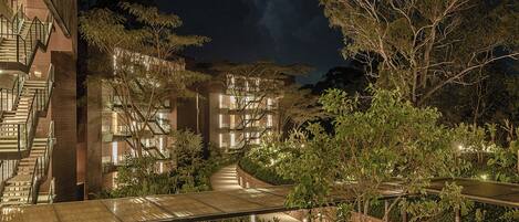 A multi-story hotel with a central courtyard, surrounded by trees and a stormy sky.
