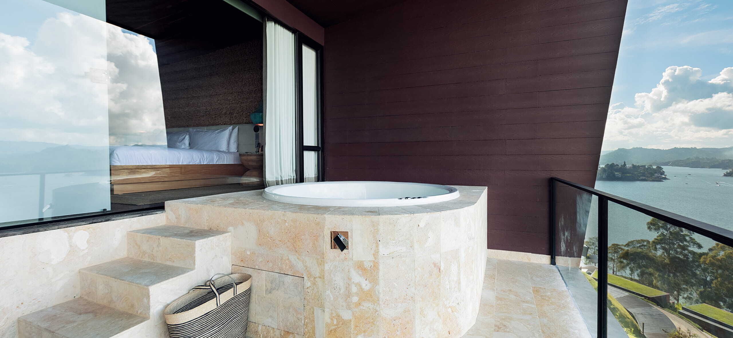 Un baño moderno con una bañera independiente, un banco de madera y vistas a un lago.