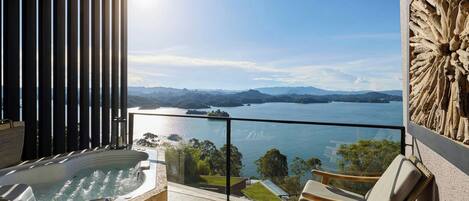 Ein Balkon mit Whirlpool, Sitzgelegenheiten und Blick auf einen See und Berge.