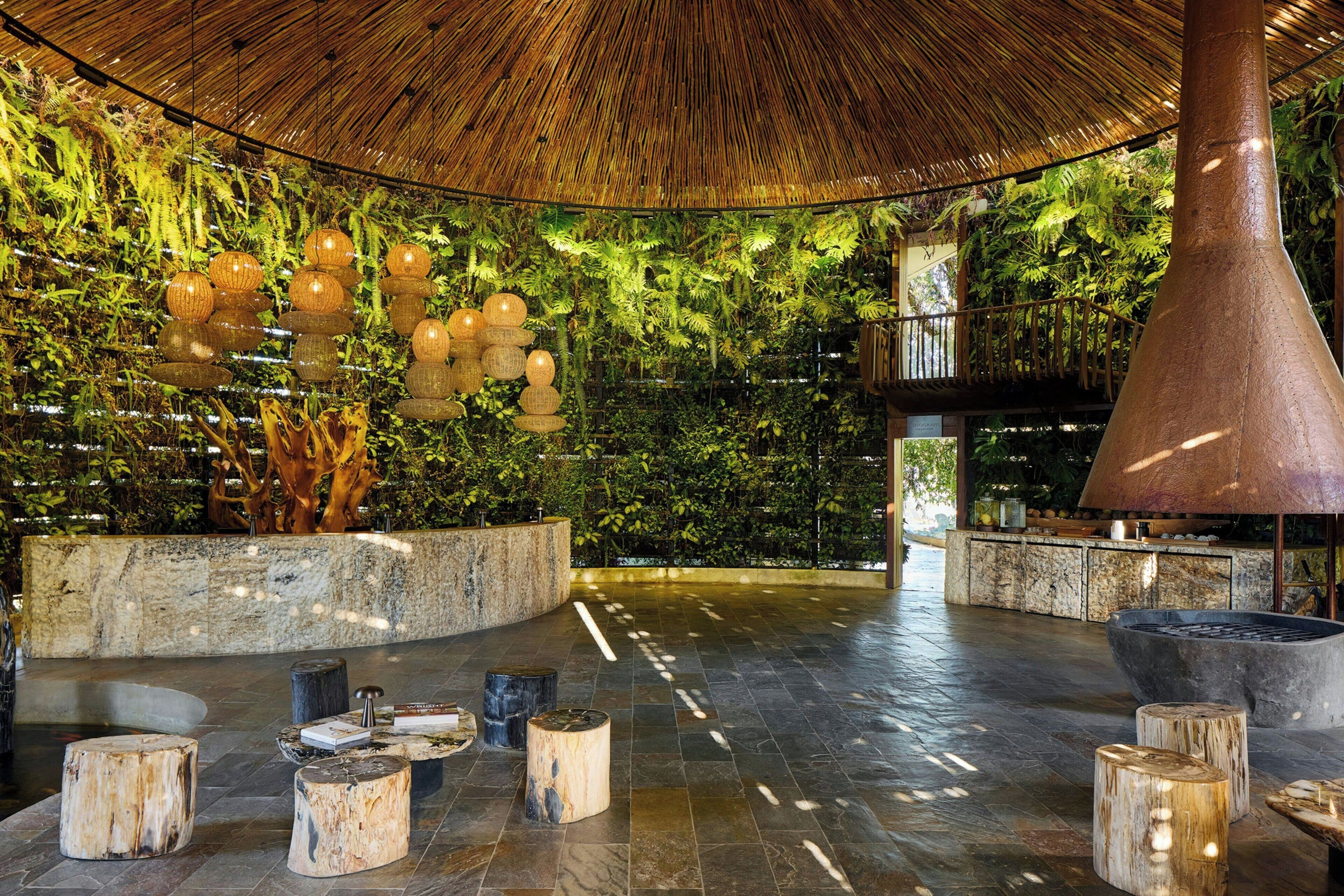 A spacious indoor area with a high ceiling, a large central column, and a wall of greenery.