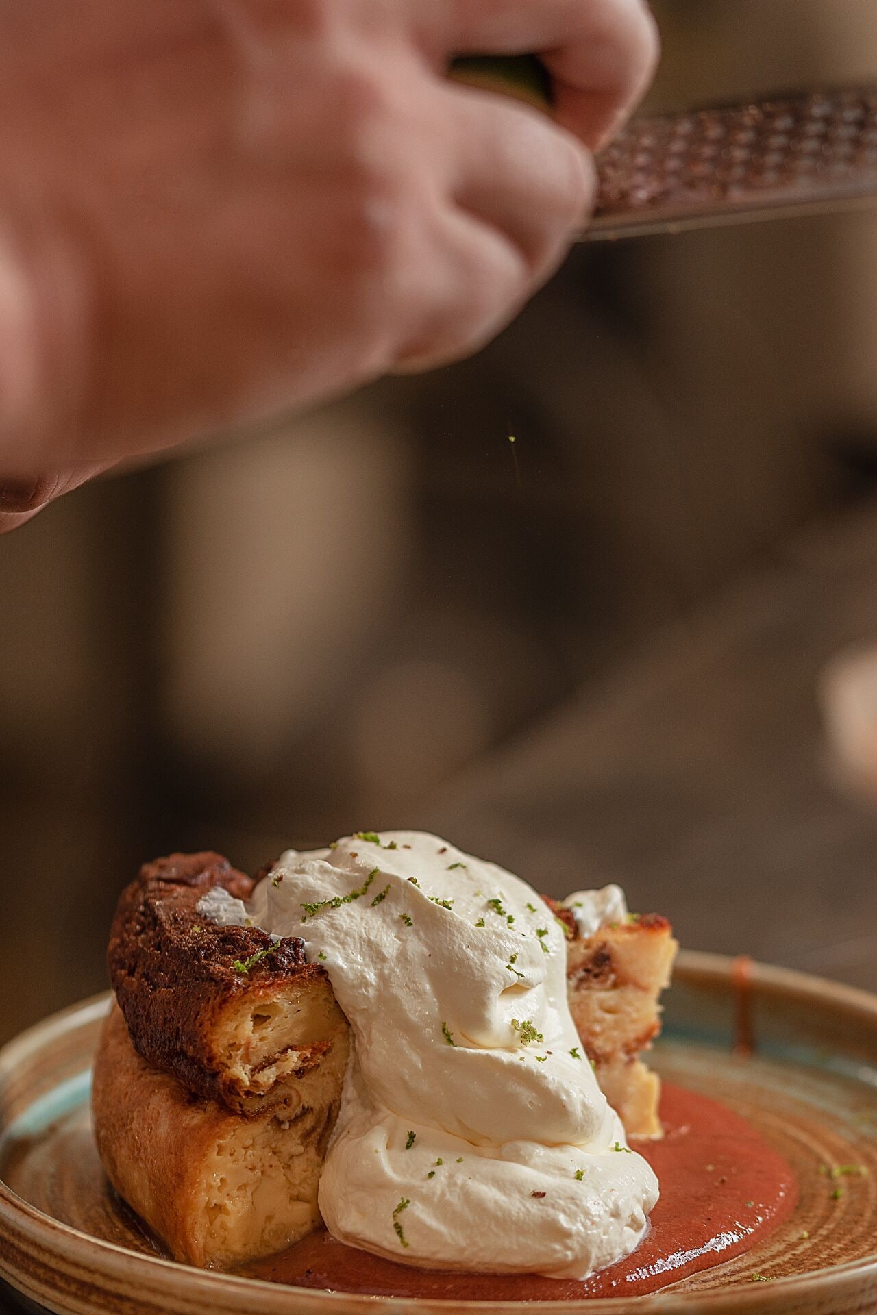 A close-up of a dessert with a pastry and whipped cream, garnished with herbs.