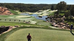 A golf course with bunkers, water hazards, and a golfer in the foreground. - 2BR Condo Near SDC | Lake Views (Branson)