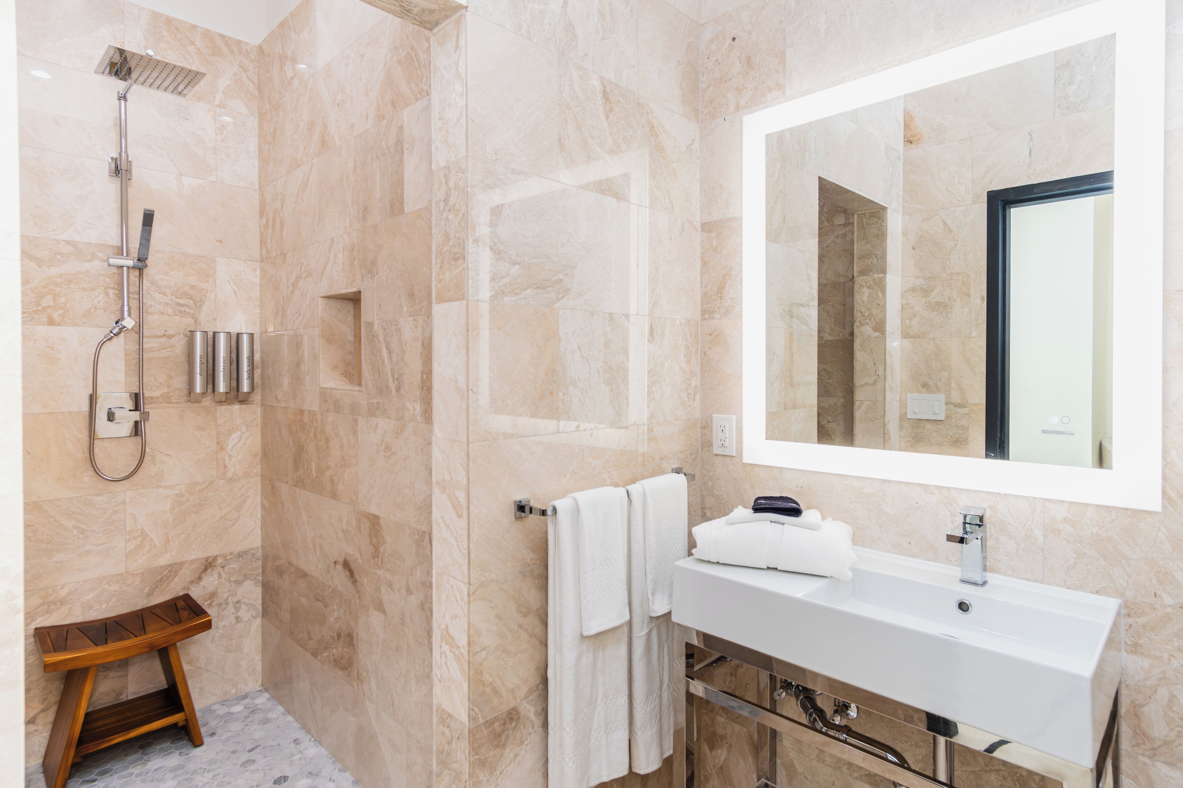 A modern bathroom with a shower, a sink, and a mirror.