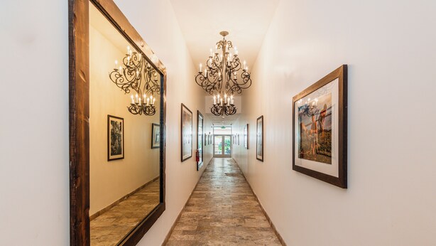 A hallway with a chandelier, framed artwork, and a large mirror. - The Link Hotel South Beach (Miami Beach)
