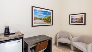 A room with a kitchenette, a desk, two chairs, and two framed pictures on the wall. - The Link Hotel South Beach (Miami Beach)