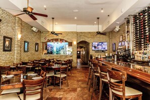 A restaurant interior with brick walls, wooden tables and chairs, ceiling fans, and a bar area with a wine rack. - The Link Hotel South Beach (Miami Beach)