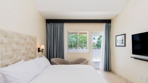 A hotel room with a large bed, a TV mounted on the wall, a chair, and a window with curtains. - The Link Hotel South Beach (Miami Beach)