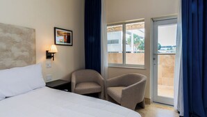 A hotel room with a bed, a chair, a nightstand, a lamp, a window, and a door leading to a balcony. - The Link Hotel South Beach (Miami Beach)