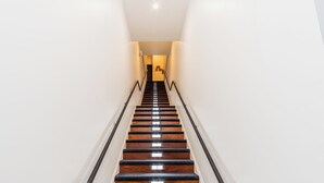 A staircase with wooden steps and black handrails, leading to a landing with a door. - The Link Hotel South Beach (Miami Beach)
