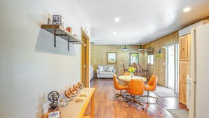 Zona pranzo con tavolo e sedie in legno, cucina con mobili in legno e angolo soggiorno con divano e tavolino.