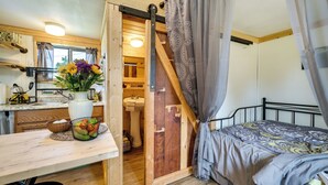 Un dormitorio con una cama, un escritorio de madera, un lavabo y un baño visible a través de una puerta abierta.