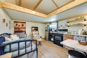 A cozy kitchen with wooden beams, a dining area, and a living space with a bed.