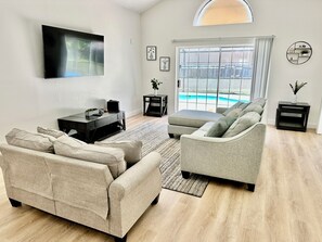 A modern living room with a sofa, a coffee table, and a TV mounted on the wall.