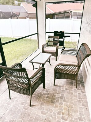 A patio area with wicker furniture, a small table, and a grill.