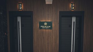 A hotel entrance with two doors labeled "Room 1/2" and "Room 3/4" and a sign for "Premium Apartments". - Premium Apartments (Gjakova)