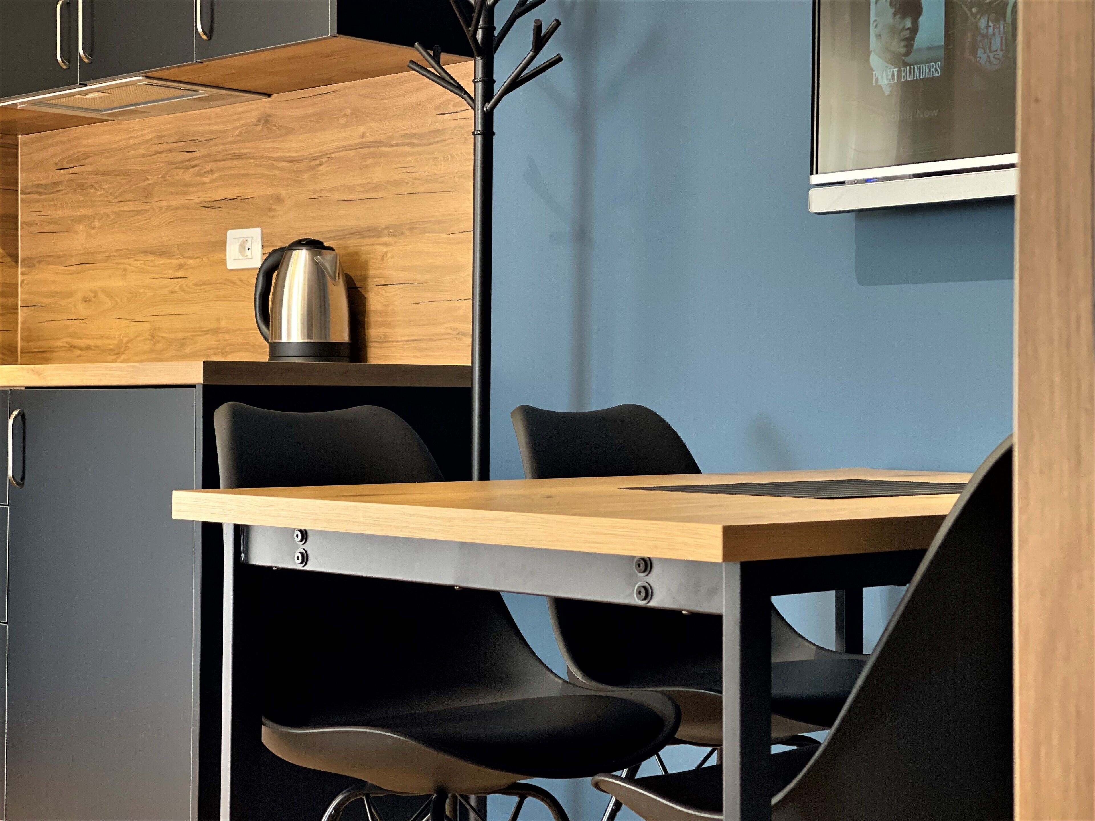 Una cocina moderna con encimera de madera, sillas negras y una tetera.
