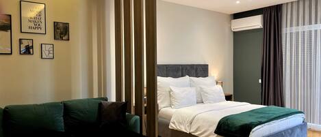 A modern bedroom with a bed, a green sofa, and a wooden partition.