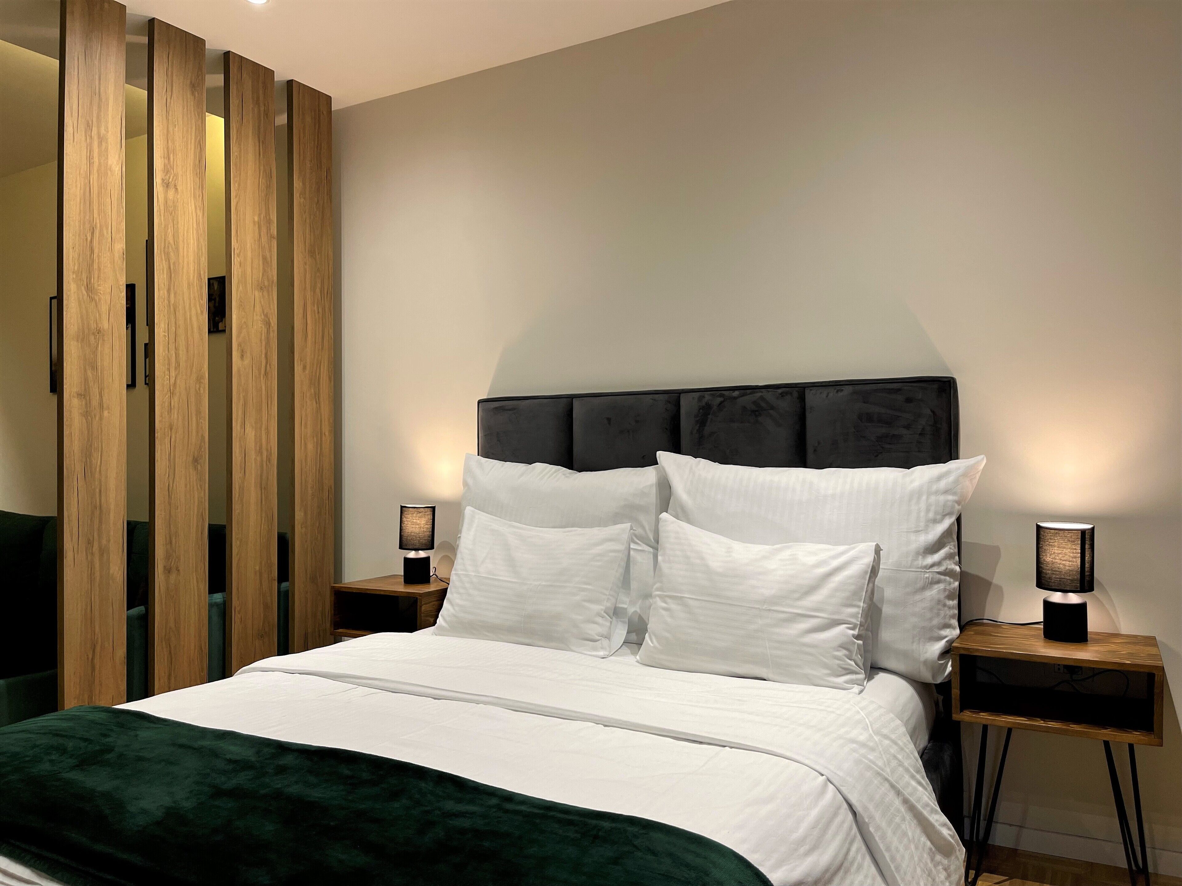 Un dormitorio moderno con una cama grande, dos mesitas de noche y un armario de madera.